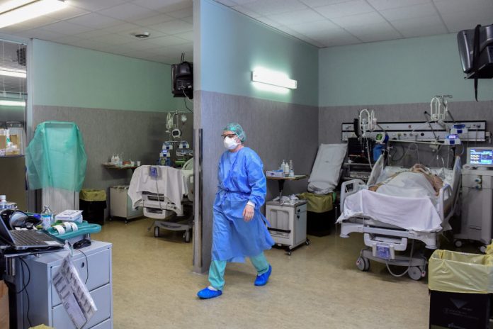 Medical worker wearing a protective mask and suit and a patient suffering from coronavirus disease (COVID-19) are seen in an intensive care unit at the Oglio Po hospital in Cremona