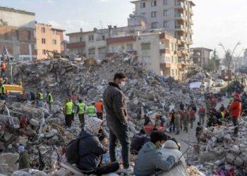 People stand on top of rubble of collapsed buildings during rescue operations  in Hatay on February 12, 2023, after a 7,8 magnitude earthquake struck the border region of Turkey and Syria earlier in the week. (Photo by BULENT KILIC / AFP)