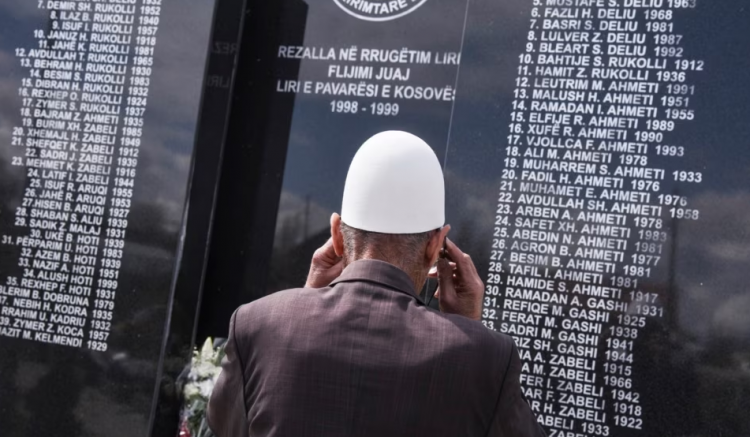 Një burrë shikon pllakën përkujtimore ku janë shkruar emrat e personave të vrarë gjatë luftës më 1999 në fshatin Rrezallë