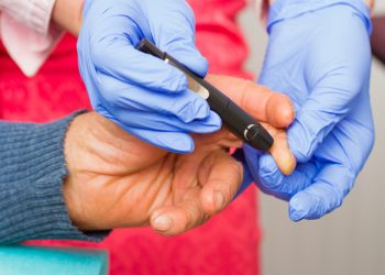 Close-up of an old man's routine medical examination, checking blood sugar level.