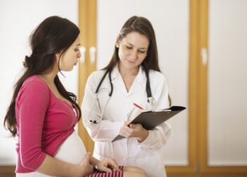 Young pregnant woman with doctor in ambulance.