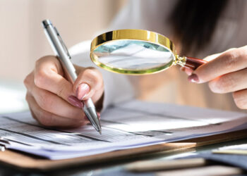 Corporate Auditor Using Magnifying Glass For Tax Fraud Audit