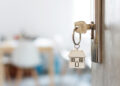 Key with keychain in a house shape in the door keyhole. Buy new home concept. Real estate market.