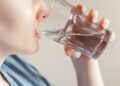 Woman drinks clean water. World Water Day. Health care concept. Diet and detox, increase metabolism. Hand holds drinking glass of water.