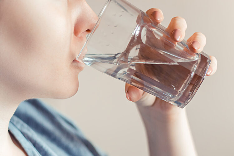 Woman drinks clean water. World Water Day. Health care concept. Diet and detox, increase metabolism. Hand holds drinking glass of water.