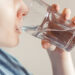Woman drinks clean water. World Water Day. Health care concept. Diet and detox, increase metabolism. Hand holds drinking glass of water.