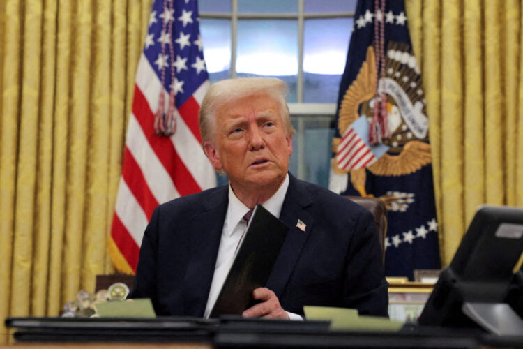 FILE PHOTO: U.S. President Donald Trump signs documents as he issues executive orders and pardons for Jan. 6 defendants in the Oval Office at the White House on Inauguration Day in Washington, U.S., January 20, 2025. REUTERS/Carlos Barria/File Photo