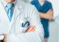 Professional medical team posing, doctor's lab coat and stethoscope close up, selective focus